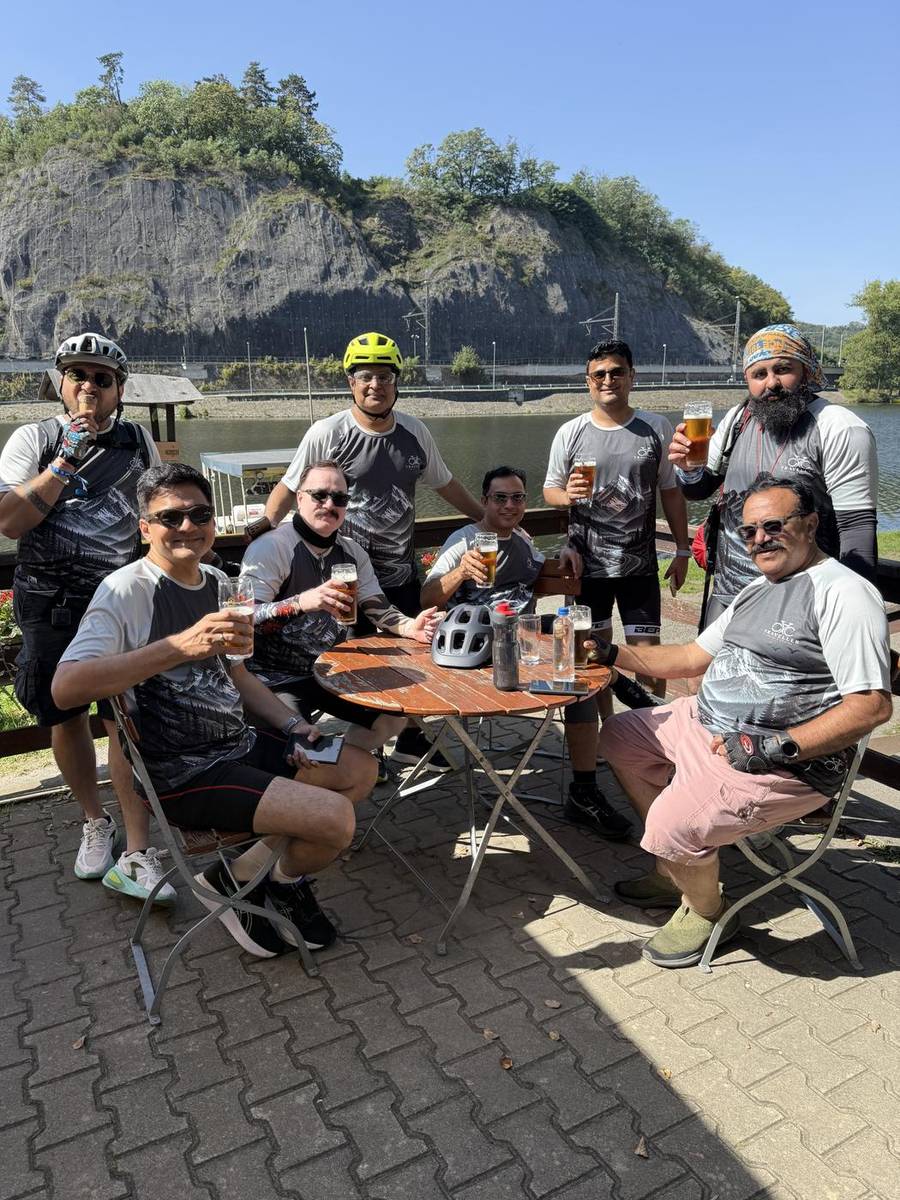 Riders raising a glass at a riverside stop on the Vltava