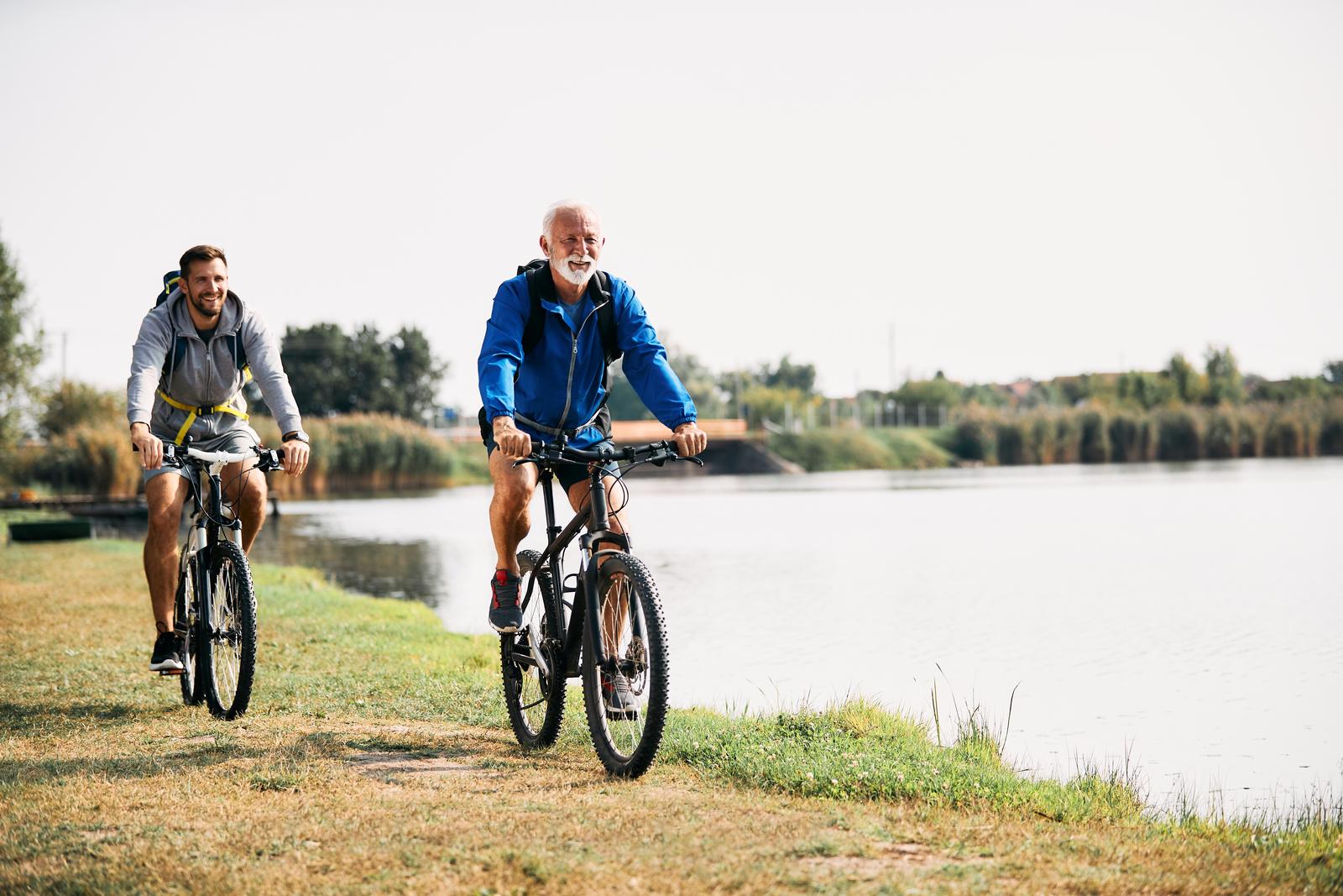 Two cyclists riding beside a lake